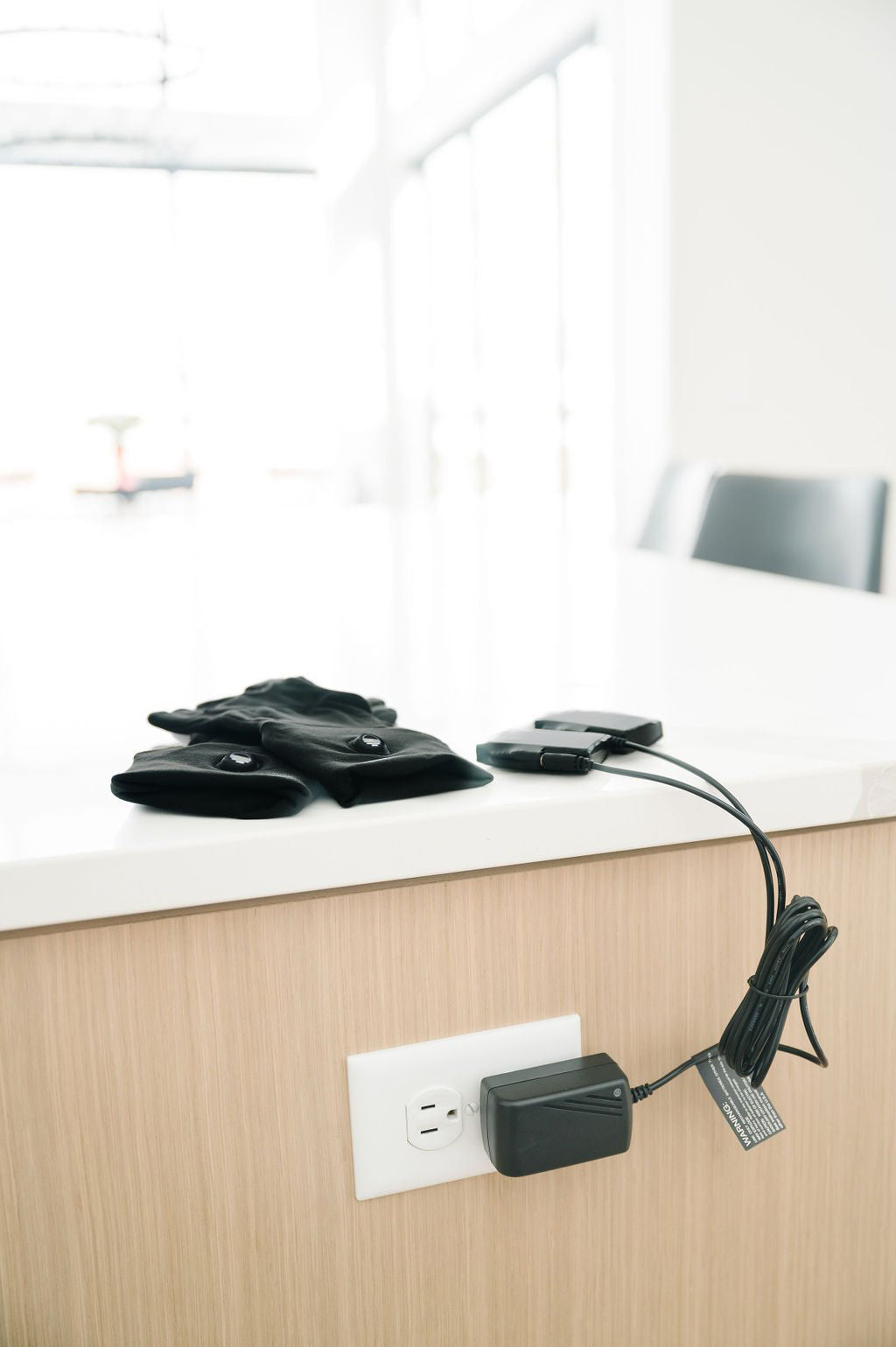 Toasty Touch heated gloves on a counter with 7V rechargeable batteries plugged into a wall charger